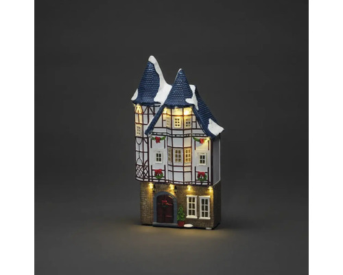 Beleuchtetes Weihnachtshaus mit Dekoration und Schnee auf dem Dach