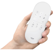 Eine Hand hält eine Fernbedienung für eine Toilette der Marke Grohe.