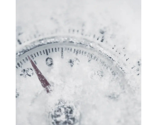 Nahaufnahme eines Thermometers, das mit Schnee bedeckt ist und eine Temperatur unter Null anzeigt.