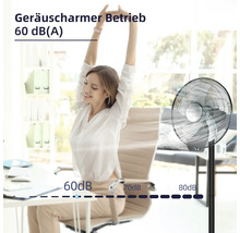 Szene mit einer Frau an einem Schreibtisch und einem Standventilator, der einen geräuscharmen Betrieb von 60 Dezibel bietet