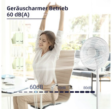Eine Frau sitzt entspannt am Schreibtisch neben einem leisen Standventilator