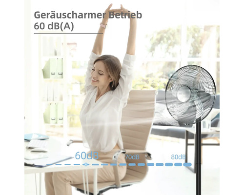 Eine Frau dehnt sich neben einem Ventilator im Büro, der einen geräuscharmen Betrieb mit 60 Dezibel bietet.