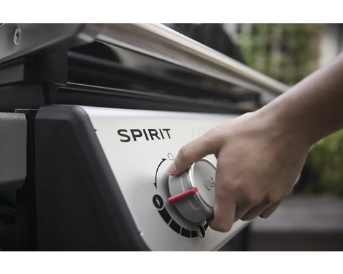 Nahaufnahme eines Gasgrills der Marke Spirit, bei dem eine Hand einen Regler bedient.