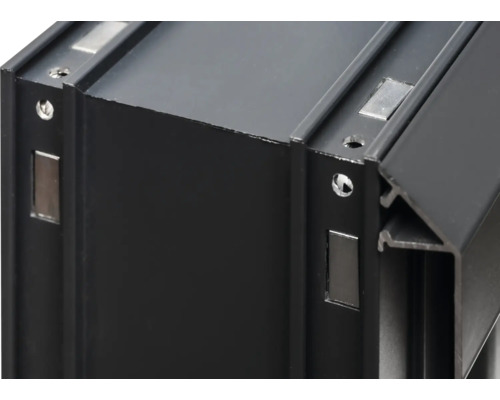 Detailansicht eines schwarzen Aluminiumprofils mit Magneten und Schraubenlöchern.