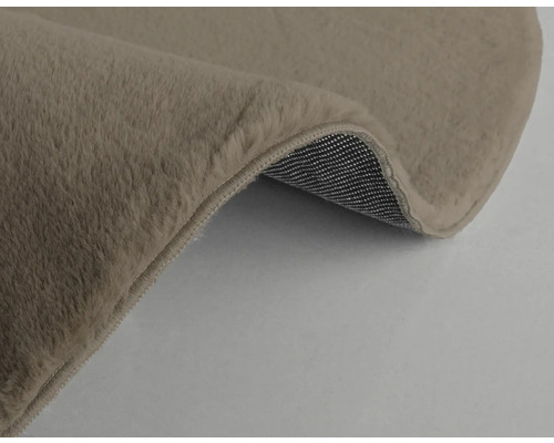 Detailansicht eines beigen Teppichs mit weicher Oberfläche und gewebter Rückseite