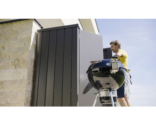 Person bereitet Grill vor, Abstellraum im Hintergrund