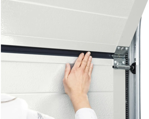 Detailaufnahme einer Hand, die eine Garagentordichtung an einem Garagentor anbringt.