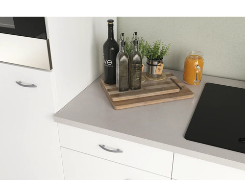 Küchenstillleben mit Schneidebrettern, Ölflaschen, Kräutern und einem Glas Saft auf einer Küchentheke.