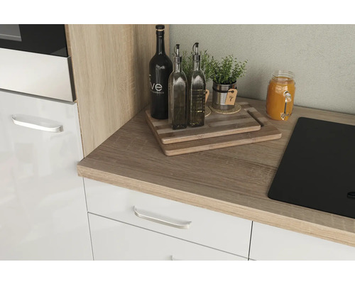 Küchenecke mit Schneidebrettern, Ölflaschen, Kräutern und Einmachglas auf Arbeitsplatte