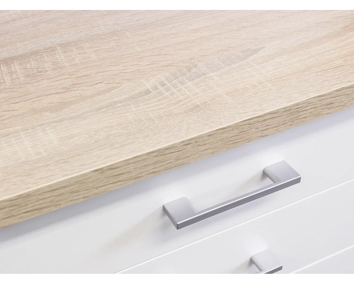Detailaufnahme eines Möbelstücks mit einer Arbeitsplatte in Holzoptik und weißen Schubladen mit silberfarbenen Griffen