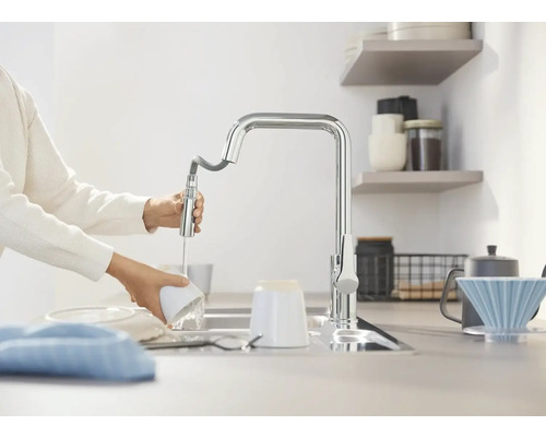 Eine Person spült Geschirr mit einer Küchenarmatur.