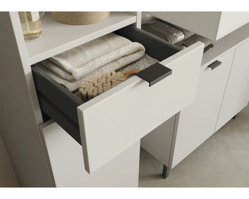 Badezimmermöbel mit geöffneter Schublade, gefüllt mit Handtüchern und Bürste.