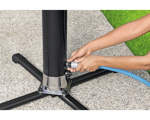 Frau schließt Wasserschlauch an Wasserzapfsäule im Garten an