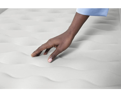 Nahaufnahme einer Hand, die eine Matratze berührt, Textur und Komfort demonstrierend.