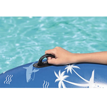 Detailaufnahme einer Hand, die sich an einem Haltegriff einer blauen Pool-Luftmatratze mit Hai- und Palmenmotiven festhält