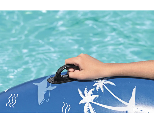 Detailaufnahme einer Hand, die sich an einem Haltegriff einer blauen Pool-Luftmatratze mit Hai- und Palmenmotiven festhält