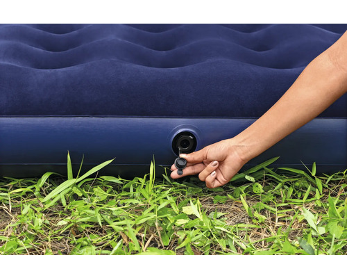 Aufblasbare Matratze mit Hand am Ventil auf Gras