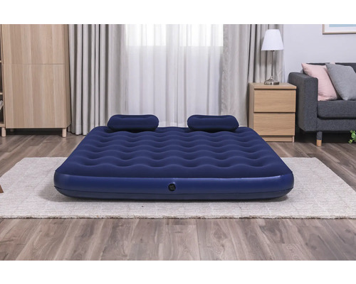 Aufblasbares Gästebett mit zwei Kissen auf einem Teppich in einem Raum.