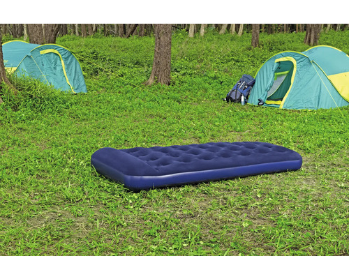 Campingplatz mit Luftmatratze, Zelten und Rucksack im Grünen