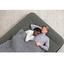 Luftmatratze mit zwei schlafenden Personen unter einer Decke auf einem Teppich