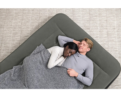 Luftmatratze mit zwei schlafenden Personen unter einer Decke auf einem Teppich