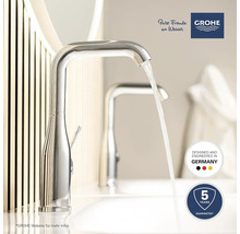 Nahaufnahme einer glänzenden Armatur mit fließendem Wasser im Badezimmer. Grohe Logo. Fünf Jahre Garantie. Hergestellt in Deutschland.