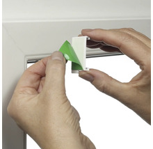 Person entfernt Schutzfolie von Fensterhaken zur Montage