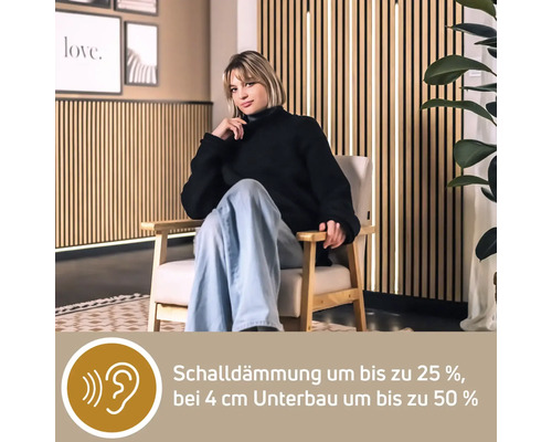 Eine Frau sitzt auf einem Stuhl vor einer Holzpaneelwand zur Schalldämmung.