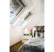 Schlafzimmer mit Dachfenstern, Nachttischlampe, Tulpen und einem Bett mit Kissen