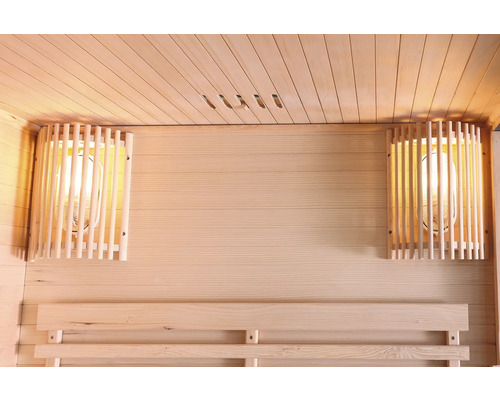 Innenraum einer Sauna mit Holzwänden, einer Sitzbank und zwei Lampen mit Holzschutzgittern.
