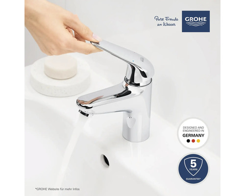 Eine Hand betätigt einen verchromten Waschtischmischer von Grohe, Wasser fließt. Garantie: 5 Jahre. Hergestellt in Deutschland. Grohe Logo.