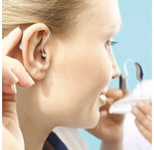 Frau setzt ein Hinter-dem-Ohr Hörgerät ein