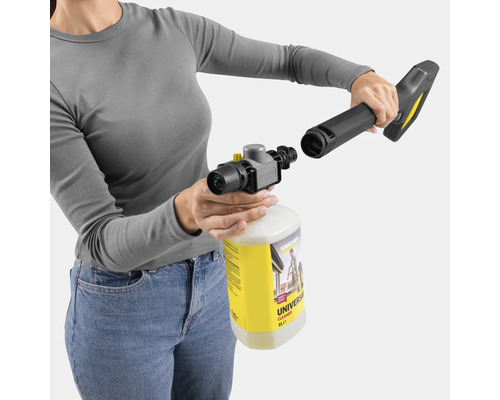 Eine Frau montiert einen Schaumsprüher auf eine Kärcher-Düse mit einer Flasche Universalreiniger.