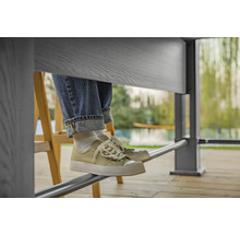 Person sitzt am Tisch mit Jeans und Turnschuhen