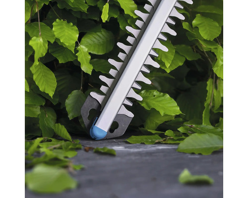 Nahaufnahme einer Heckenschere vor Büschen.