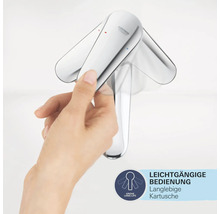 Eine Hand bedient einen verchromten Wasserhahn von Grohe