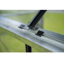 Detailansicht eines Gewächshauses mit Aluminiumrahmen und schwarzen Befestigungsklammern.