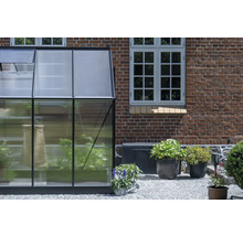 Gewächshaus mit Pflanzen neben einem Backsteingebäude