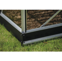 Detailansicht eines Gewächshausfundaments auf einer Rasenfläche.