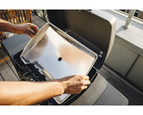 Edelstahl Grillwanne wird in einen Grill eingesetzt.