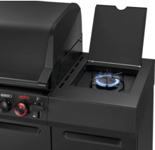 Detailansicht eines schwarzen Gasgrills mit geöffnetem Seitenkocher und aktivierter Flamme.