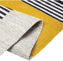 Detailansicht eines Teppichs mit Streifenmuster und aufgerolltem Ende