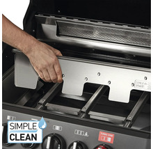 Eine Person setzt eine Edelstahl-Grillplatte in einen Gasgrill ein