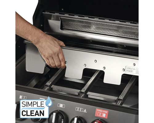 Eine Person setzt eine Edelstahl-Grillplatte in einen Gasgrill ein