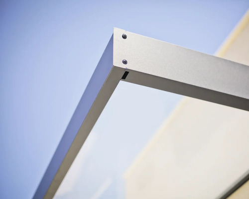 Detailaufnahme der Eckverbindung eines Vordachs mit Metallrahmen und Glaselement.
