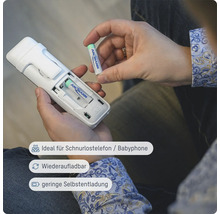 Eine Person legt eine Ansmann Batterie in ein schnurloses Telefon ein.