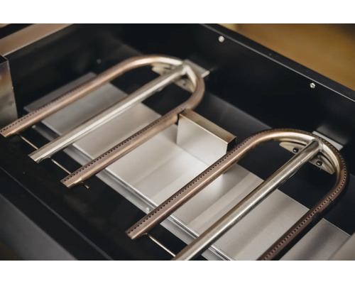Detailaufnahme von Grillbrennern aus Metall in einem Grill