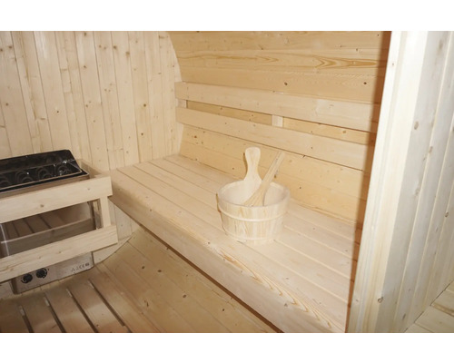 Innenansicht einer Sauna mit Holzbänken, Saunaofen und Holzkübel mit Schöpfkelle