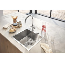 Küchenspüle aus Edelstahl mit Armatur auf einer Küchentheke mit Speisen und Getränken