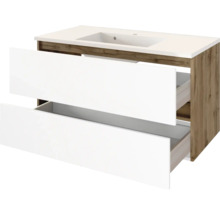 Waschtischunterschrank mit zwei weißen, geöffneten Schubladen, integriertem Waschbecken und Korpus in Holzoptik.